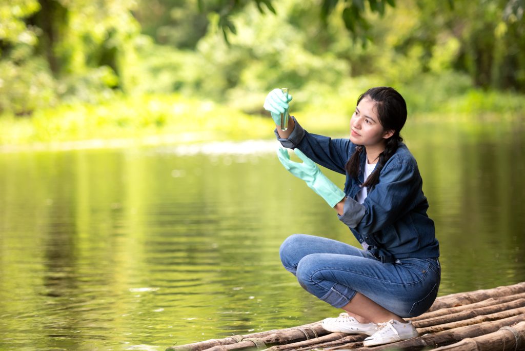 Asian student biology taking and testing sample of natural river water.  Experts science women keep water for research analysis in the laboratory.  Environmental pollution Concept